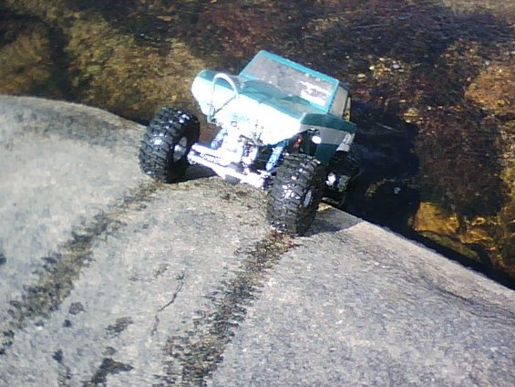 Toy off-road vehicle with large tires on a rock near water