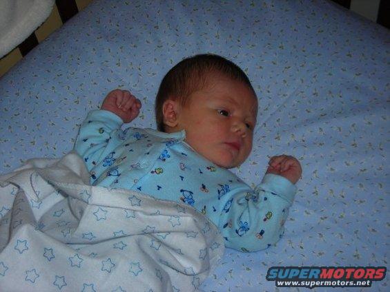 Baby in blue pajamas with teddy bears, lying in a crib