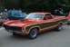 1970 Ford Ranchero - A classic red Ford Ranchero with wood grain trim is displayed at an outdoor car show.