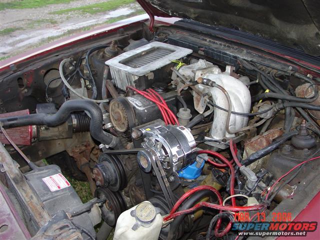 1984 Ford Mustang engine bay with V8 engine, red spark plug wires, and air intake