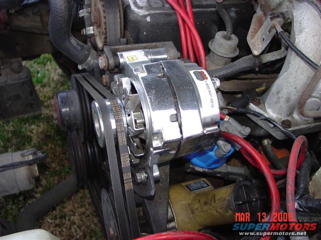 Chrome alternator with black belts and red wires on engine