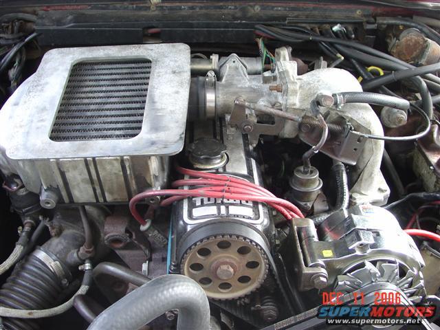 Engine bay with intercooler and turbocharger. Visible text: TURBO, DEC 11 2006, SUPERMOTORS