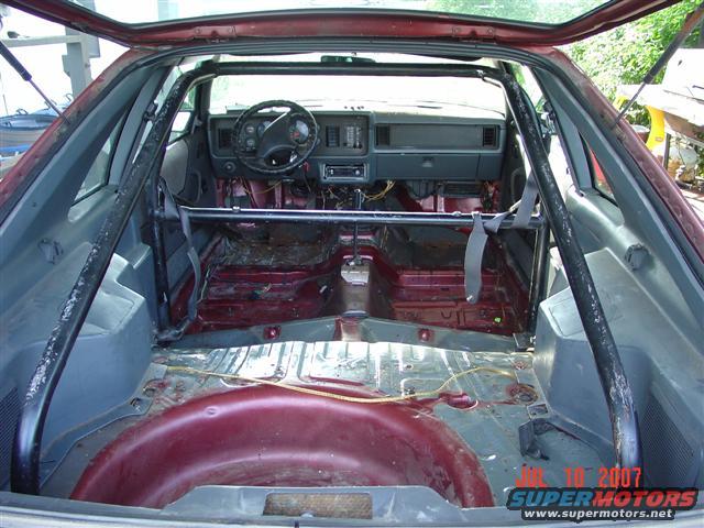 1984 Ford Mustang interior with roll cage, stripped rear seats and cargo area