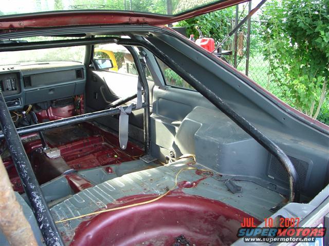 1984 Ford Mustang interior with roll cage and stripped-down interior