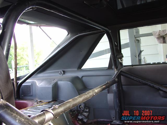 1984 Ford Mustang interior with a black roll cage, grey plastic trim, and a black door panel. A date stamp reads JUL 10 2007