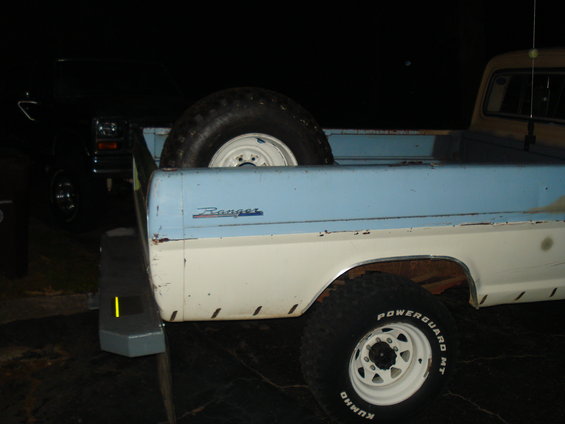 1967 Ford F-250 Ranger truck bed, white and blue, with spare tire and another truck behind it