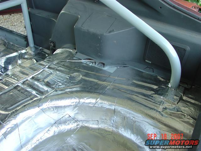 Car interior with sound deadening material on the floor and a roll cage