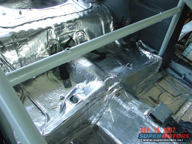 Car interior with silver sound deadening material applied to floor and rear panels, plus a roll bar