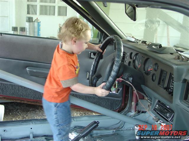 Kid steering a car. Dash and door panel visible