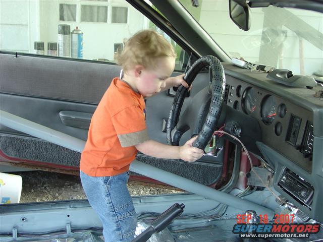 Child holding steering wheel inside car interior