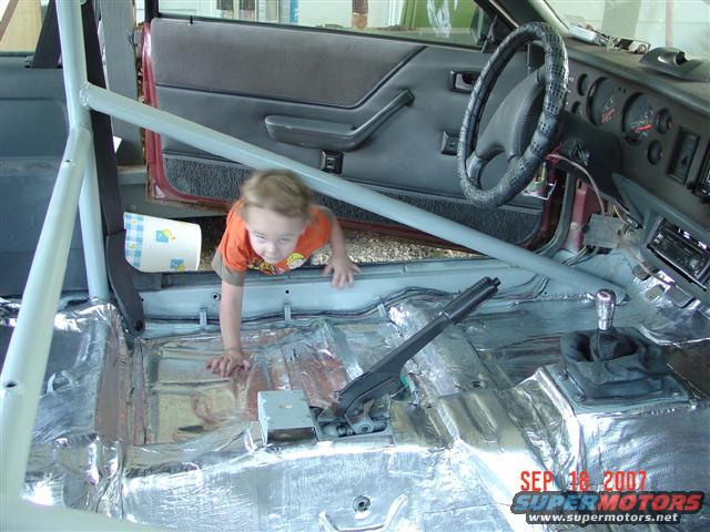 1984 Ford Mustang interior with roll cage and child crawling
