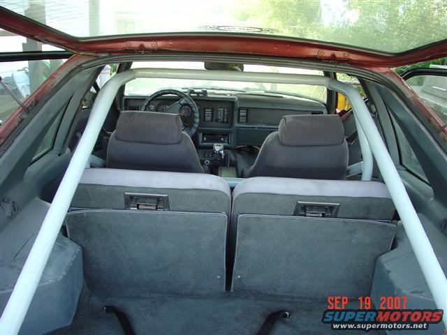 1984 Ford Mustang interior with roll cage, grey seats, and dashboard visible