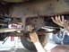 1979 Ford Bronco - Mechanic working on the undercarriage of a large truck, focusing on suspension parts.