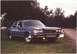 1994 Ford F-250 - This blue sedan, possibly from the 1980s, is parked on a grassy area next to a dirt road.