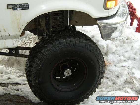 White 1994 Ford Bronco front fender and large tire in snow