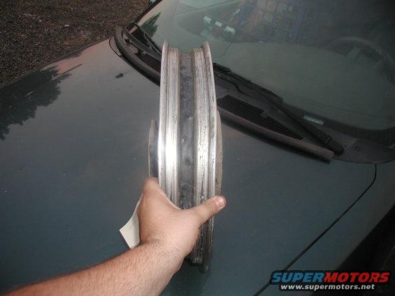 Hand holding a motorcycle wheel rim over a car hood