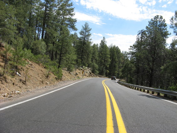 Car driving on a winding road through a forest, seen from the perspective of another vehicle
