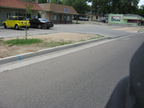 yellow off-road vehicle and black sedan parked in front of buildings