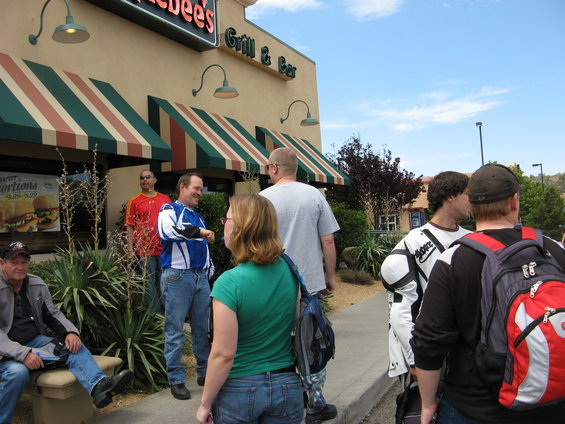 Group of people standing and sitting outside a restaurant with awnings