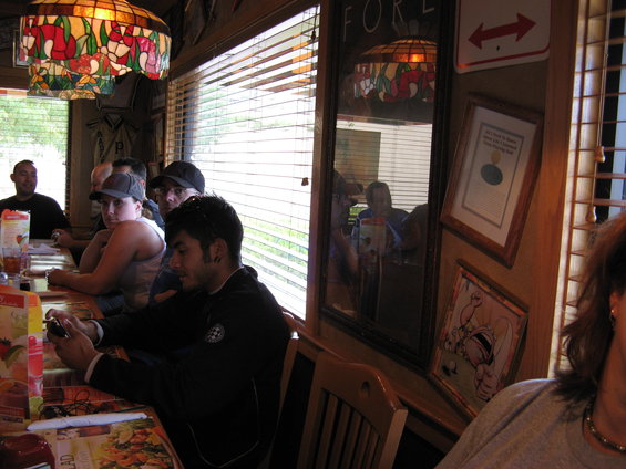 People sit at a restaurant table with menus and stained glass lamps overhead