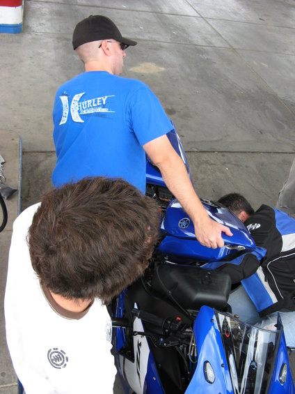 Man in blue shirt holding a blue motorcycle fuel tank with Yamaha logo