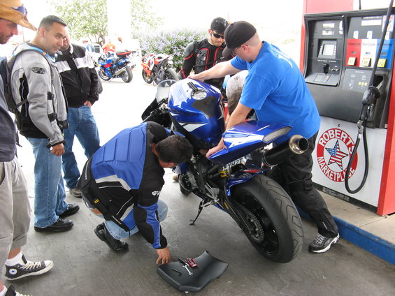 Blue sport motorcycle at gas station, rear view. People gathered around