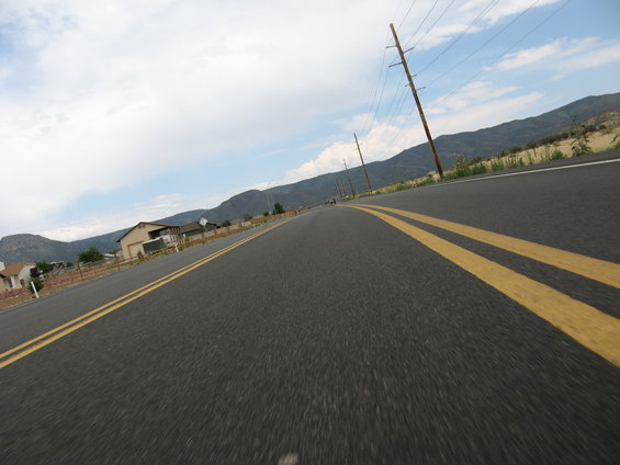 Road with double yellow lines, houses and mountains in the background