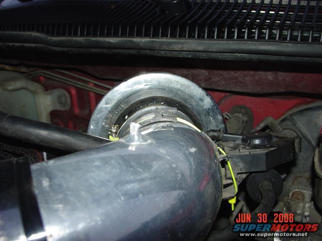 Close-up of a metal intake tube with a clamp and sensor attached, showing a date stamp