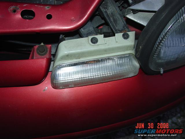 Red car front bumper with a clear turn signal and part of a headlight assembly visible