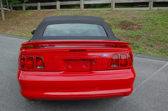 Red convertible with black top, rear view. Ford emblem visible on trunk lid
