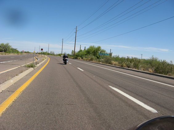 Motorcycle riding on a highway in a desert landscape under a clear blue sky