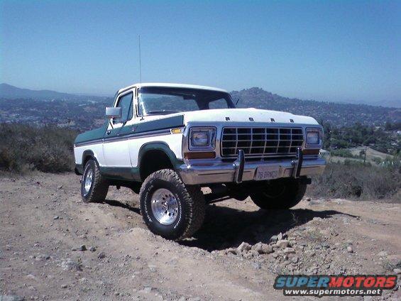 1978 Ford Bronco parked on a dirt hill with a scenic background