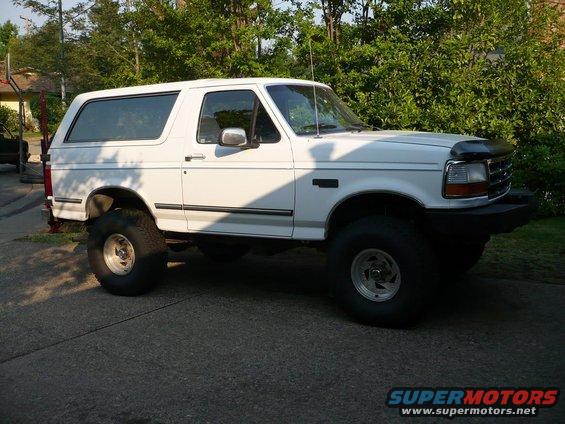 White 1992 Ford Bronco with lifted suspension and large tires, viewed from the front three-quarter angle