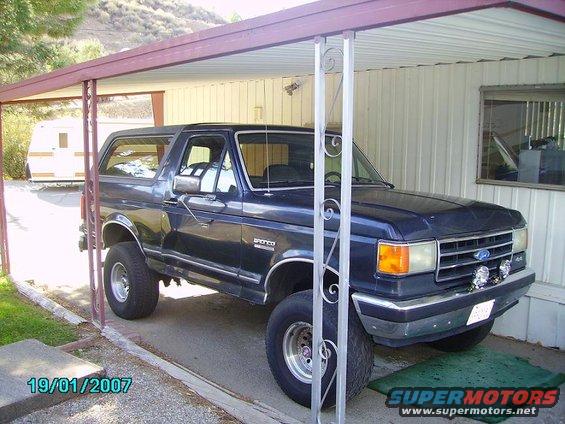 Dark blue 1990 Ford Bronco parked under a carport, 3q-front view