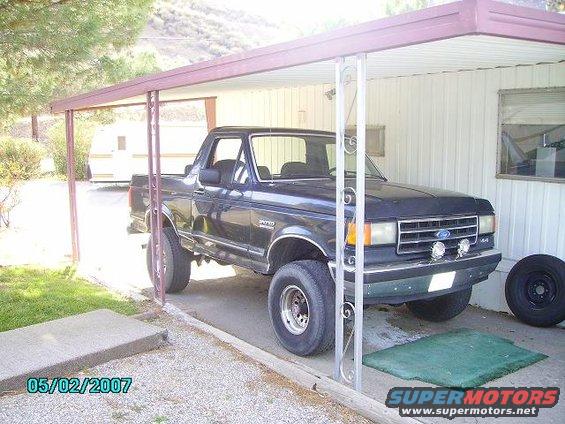 1990 Ford Bronco parked under a carport, front quarter view