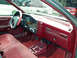 1989 Ford Thunderbird - The interior of a car shows red upholstery and a dashboard with wood trim details.