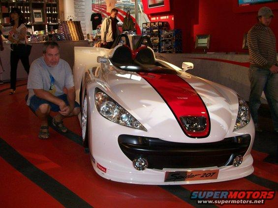 White sports car with red stripe and 'Spider 207' badge on front bumper