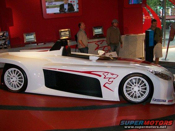 White sports car with red jaguar graphic on the side, on display indoors