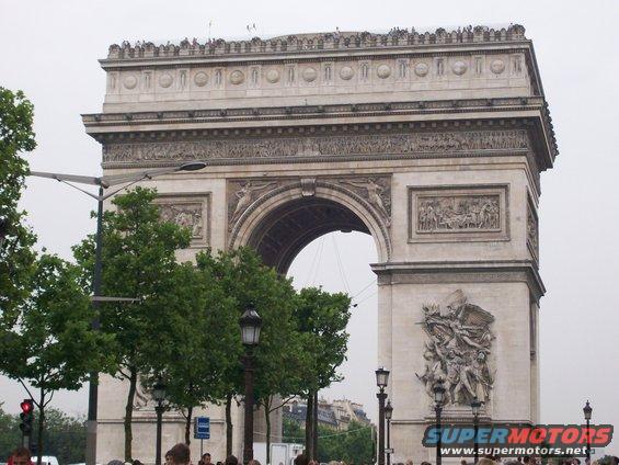 Arc de Triomphe monument in Paris with trees and streetlights in foreground