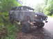1979 Ford Bronco - This heavily modified 1978 Ford Bronco features an extreme lift kit and camouflage paint, parked on the side of a wooded road.