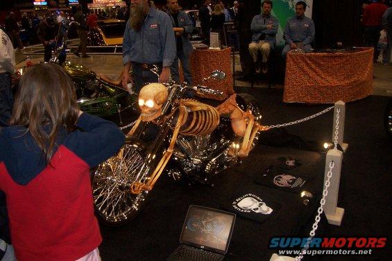 Motorcycle with skeleton rider, side view. SuperMotors.net logo visible