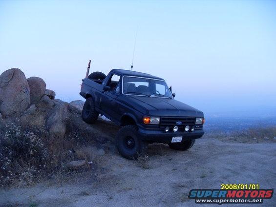 Dark blue 1990 Ford Bronco on rocky terrain, 3q-front view