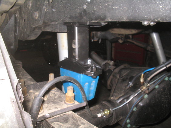 Undercarriage view of a blue suspension component attached to a differential