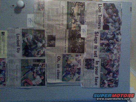 Newspaper clippings with football game photos and headlines taped to a wall