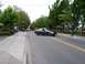 2000 Ford Crown Victoria - A dark sedan drives down a street lined with trees and sidewalks, possibly during a parade event.