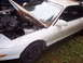 1993 Ford Probe - A white coupe sits with its hood open, revealing the engine compartment, and is covered in leaves and debris.