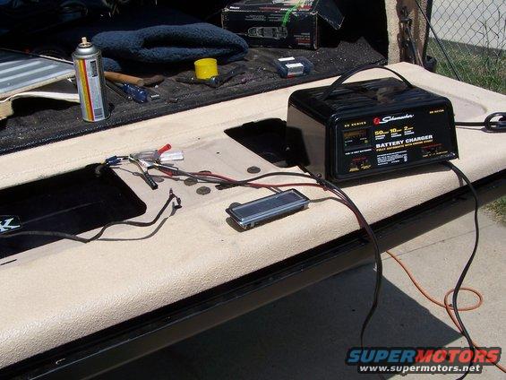 Tailgate open with a Schumacher battery charger, spray can, and tools laid out