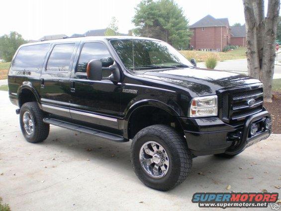 Black Ford Excursion SUV parked on a driveway. It has chrome wheels and a bull bar on the front