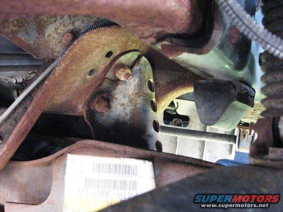 Close-up of rusty vehicle frame components and a label with a barcode