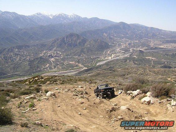 Black pickup truck on a rocky, off-road trail with mountains in the background
